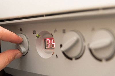 a hand adjusting settings on a boiler control panel