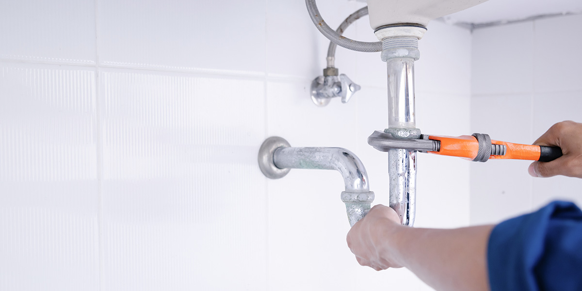 plumber with wrench tightening a pipe joint