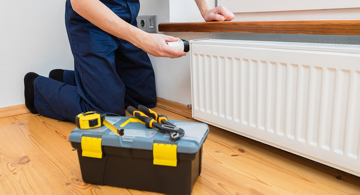 radiator being tested by an engineer in overalls with a toolbox on the floor